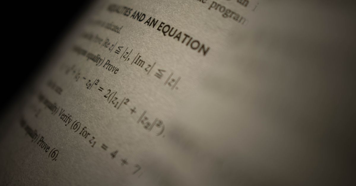 Selective focus on a mathematics textbook page with complex equations and text.
